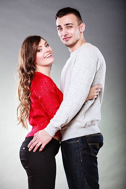 Love dating and people concept. Smiling young couple portrait on gray