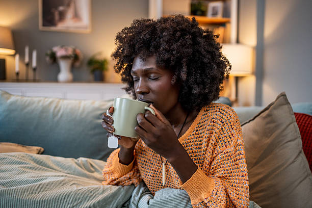 istock Young woman relaxing on sofa drinking tea at home 2220603221