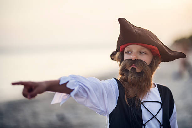istock Bearded boy dressed as a pirate leading the way on a seaside treasure quest 2220603511