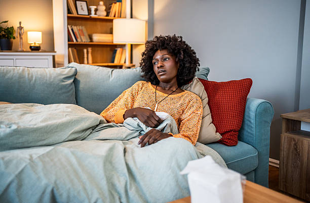 istock Sick young woman relaxing on sofa with thermometer 2220603951