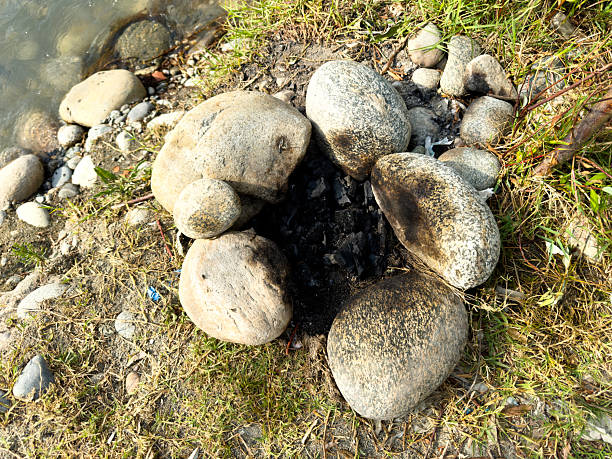 Extinguished Campfire Circle with Burnt Stones by the Riverside