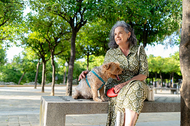 istock Retired woman lovingly touching her dog in the park 2220604380