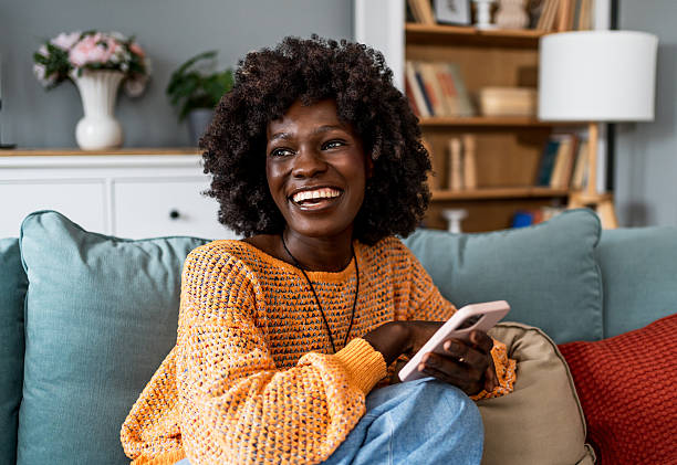 istock Young woman relaxing on sofa using smartphone and smiling 2220604525
