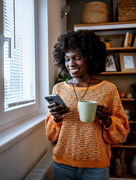 istock Young woman using smartphone and drinking coffee at home 2220605219