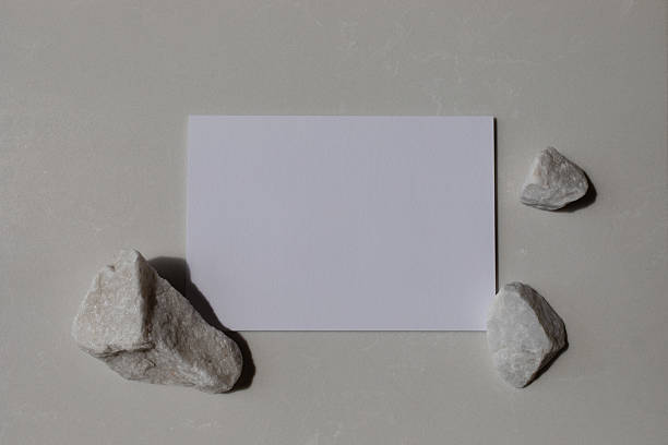 istock Empty card mockup with white decorated stones and sunlight shadows on neutral background. Aesthetic composition for minimalistic template in flat lay style. 2220607281