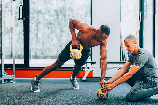 istock Personal trainer assisting athlete with kettlebell workout in gym 2220608347