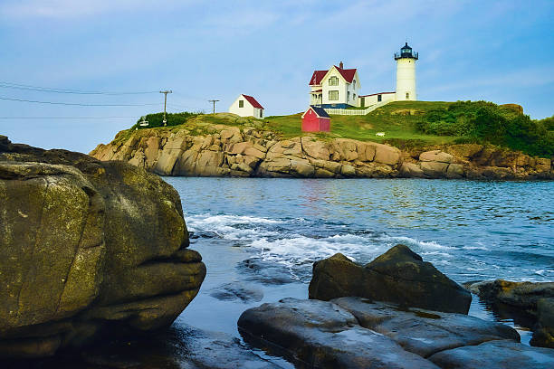 Reflection of Nubble Lighthouse in water at dusk, York, Maine, USA