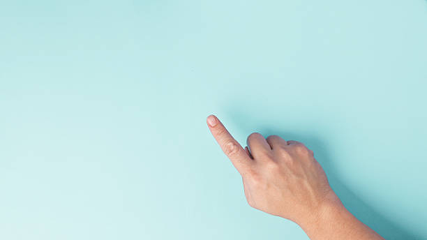 istock Hand gesture using index finger to pointing finger on empty pastel blue paper background 2220611271