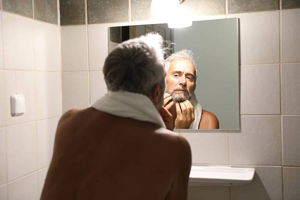 istock Senior man looking herself on mirror in the bathroom at home 2220613695