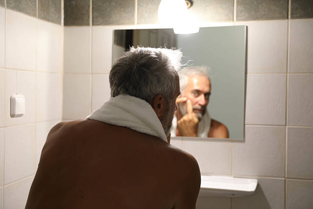 istock Senior man looking herself on mirror in the bathroom at home 2220613697