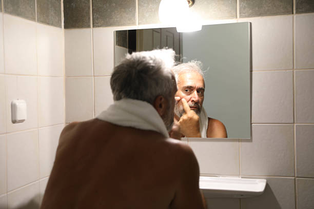 istock Senior man looking herself on mirror in the bathroom at home 2220613698