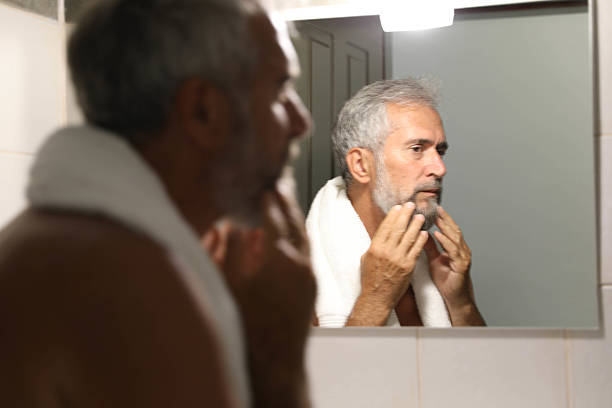 istock Senior man looking herself on mirror in the bathroom at home 2220613716