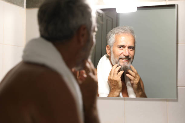 istock Senior man looking herself on mirror in the bathroom at home 2220613719