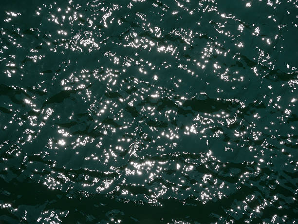 istock Water surface high contrast top view. Sun glare on water. Background abstracted wallpaper texture 2220618429