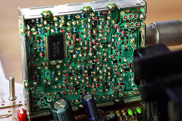 An old circuit board with intricate patterns of green and metallic components. Various resistors, capacitors, and a microchip are visible.