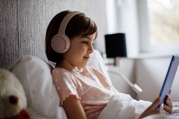 istock Cute little girl using digital tablet in bed 2220618608