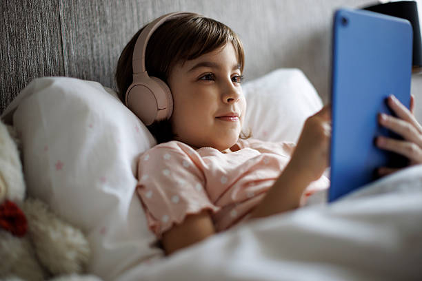 istock Cute little girl using digital tablet in bed 2220618660