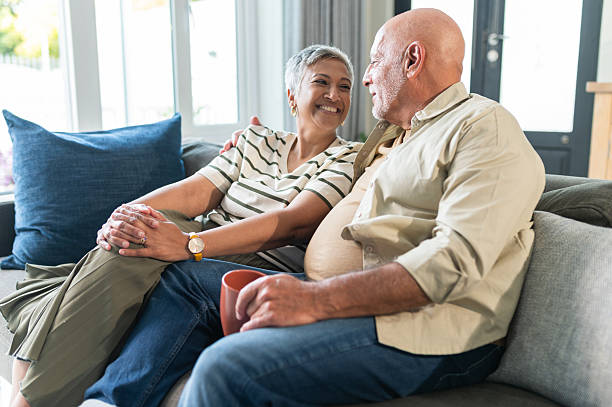 istock Cheerful senior couple relaxing on couch at home, smiling at each other in contentment 2220620249