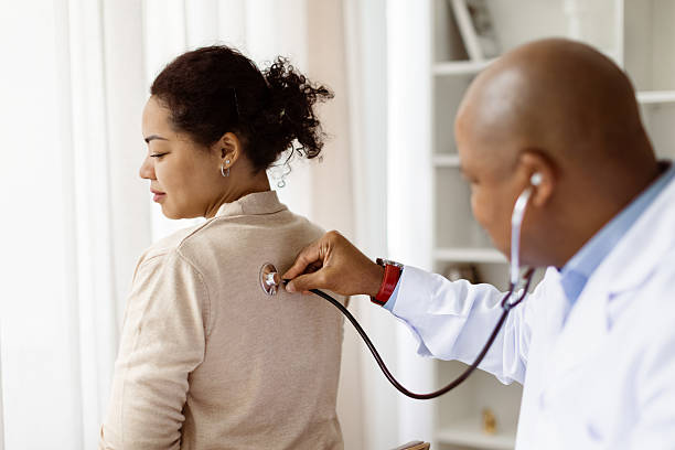 istock Doctor using stethoscope to examine the patients back during consultation in clinic 2220620757