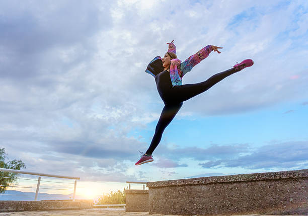 istock Young dancer performing a jump outdoors at sunset 2220621186