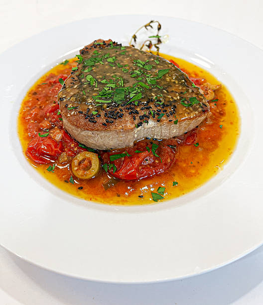 Black sesame seed crusted seared tuna steak in roasted tomato sauce with green olives.