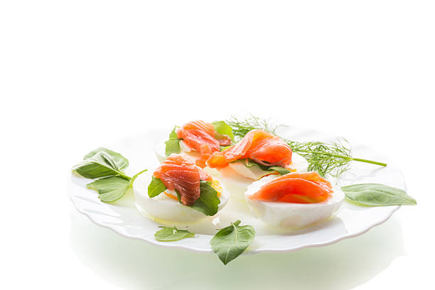Cold festive appetizer of eggs with fish slices on a white background.