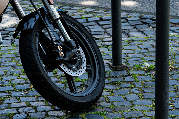 Motorcycle wheel with a disc brake on a cobblestone pavement. Close-up.