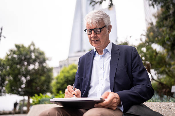 Senior Businessman Engaged in Note-Taking on Sydney Street Bench