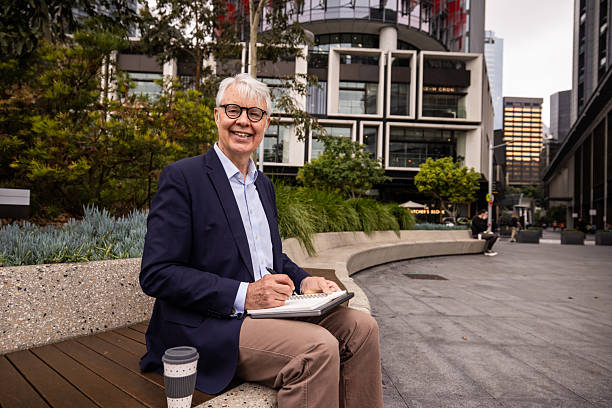 istock Senior Businessman Engaged in Note-Taking on Sydney Street Bench 2220629587