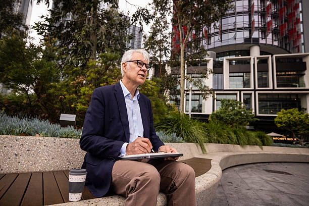 istock Elderly Businessman Planning Work on Bench in Downtown Sydney 2220629607