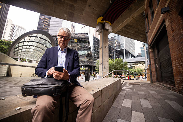 istock Mature Executive Checking Phone While Relaxing in Sydney CBD 2220629889
