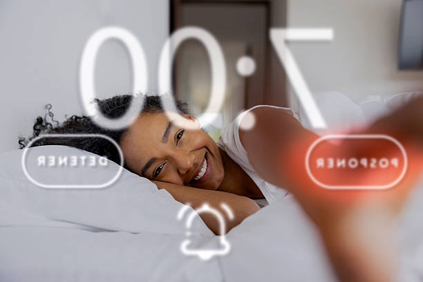 istock Happy woman in bed snoozing  her alarm clock 2220633559