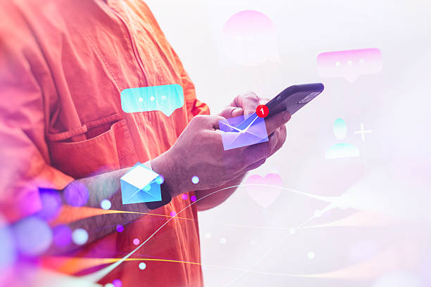 istock A man wearing a orange vest holds a smartphone displaying chat and email notifications, surrounded by vibrant digital icons. 2220634937