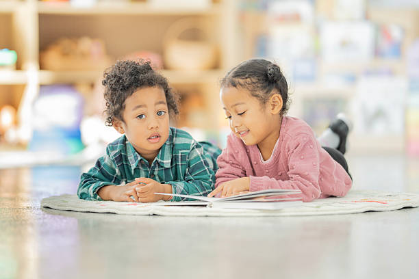 istock Two Children Reading Together on the Floor in a Bright Classroom 2220635507