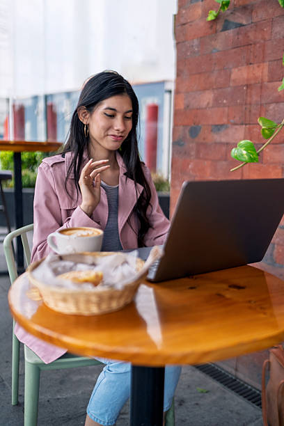 Freelancer working remotely from coffee shop enjoying cappuccino and pastry