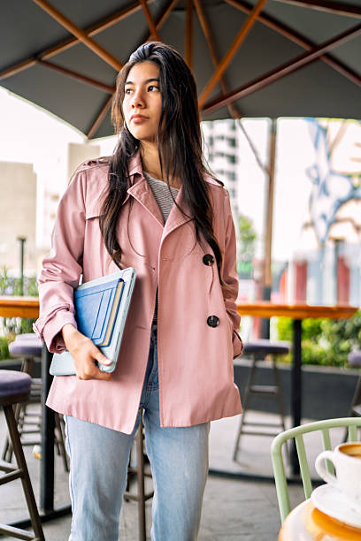 Young freelancer walking in coffee shop with laptop and notebook