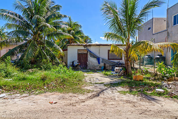 Tropical Neglect Isla Holbox, Mexico - February 27th 2019: A small building sits among palm trees, with a motorcycle parked outside. The building appears to be in disrepair. poverty mexico environment slum stock pictures, royalty-free photos & images