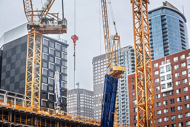 istock Tower cranes lift heavy sections on a new high rise build in downtown Montreal while existing condo towers frame the scene, capturing rapid skyline growth and the dense construction climate of Canada. 2220649742