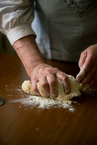 istock Old woman kneading dough on floured table 2220649978