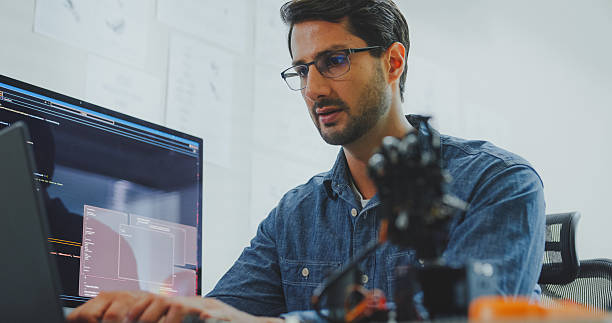istock Closeup of Black and Hispanic male engineers programmers work together on robot hand prototype, use computer control robotic arm circuit in tech office. Software developer, artificial intelligence. 2220652752