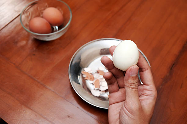 istock Close up of a man's hands holding chicken boiled egg  on the kitchen table, prepares breakfast at home 2220652895