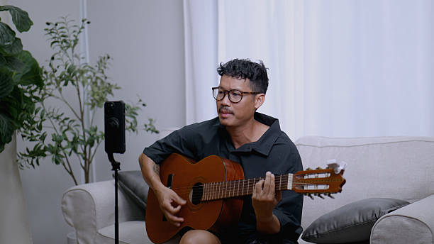 istock Asian Content Creator Goes Live with Music and Guitar. 4k 2220653329