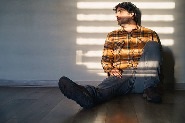 one caucasian man sitting resting looking up  full length in silhouette studio   on white background