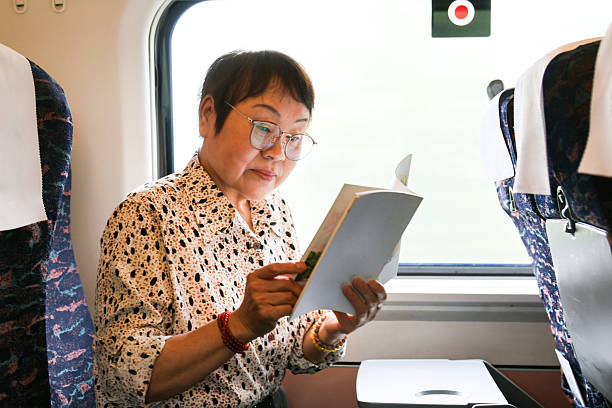 istock An elderly Asian woman is reading a book on the high-speed train. 2220656090