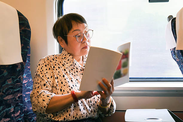 istock An elderly Asian woman is reading a book on the high-speed train. 2220656097