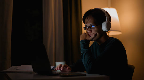 istock Quiet Midnight Work – Asian Man with Laptop and Headphones. 4k 2220656264