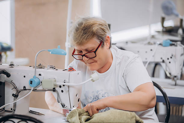 istock Seamstress elderly woman at work in a sewing workshop, small business 2220659164