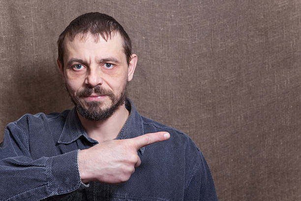 A man points his finger at the copy space. male European 40 years old, with a beard. Background from the canvas.