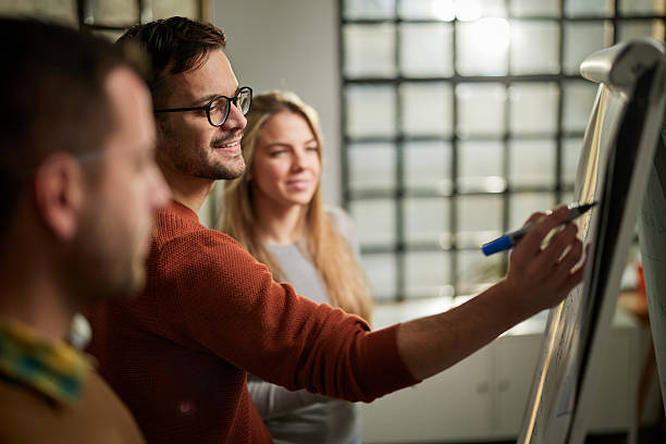 istock Happy creative man and his colleagues writing plans on whiteboard in the office. 2220668484