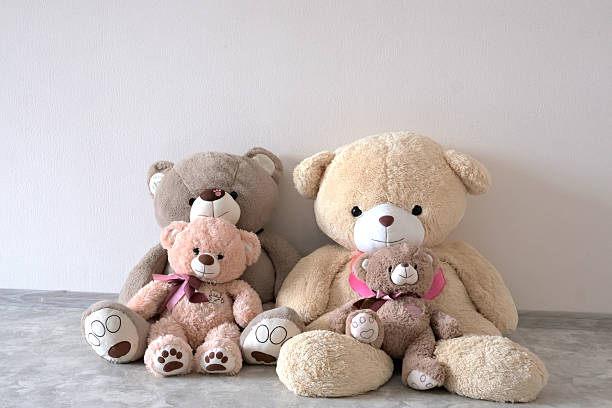 istock Cozy group of plush teddy bears, two large and two small, sitting on a neutral floor. 2220670512